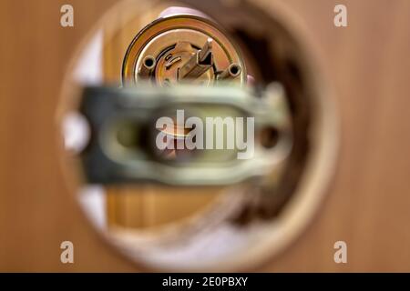 An Carpenter shoves the door handle spindle through the face bore and the latch assembly. Stock Photo