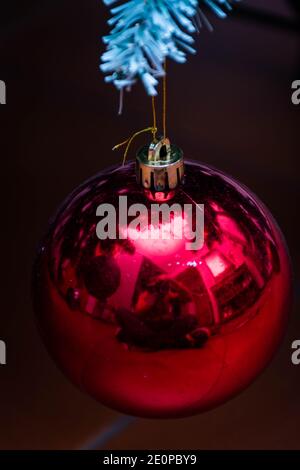 Vertical view of a powdered red Christmas ball with glitter and glitter-brilliance. Background with bokeh, Christmas card 2021, 2022. Reflected person Stock Photo