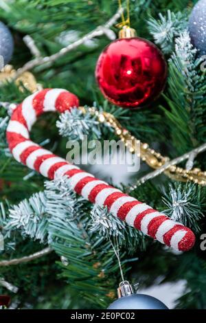 Vertical view red and white cane hanging from the Christmas tree 2021, 2022 Red ball and white, grey, silver and gold decorations. Christmas card Stock Photo