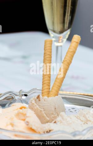 Handmade ice cream with wafers on a white background. Vertical. Tangerine ice cream and banana-rum-raisin ice cream. Glass of champagne. Bokeh backgro Stock Photo