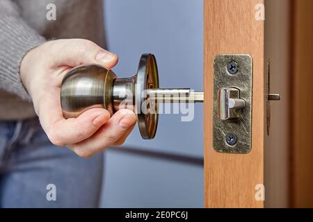 Handyman pushes the door knob spindle through the face bore and the latch assembly. Stock Photo