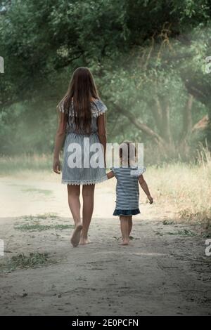 The older and younger sister for a walk in a city park. The concept of