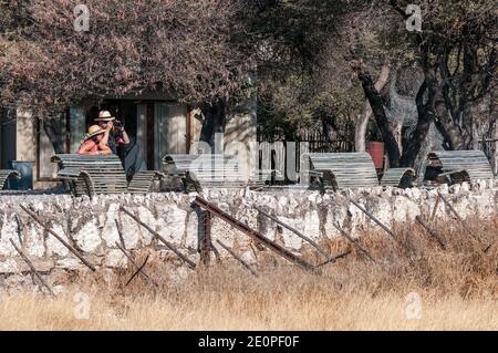 ETOSHA NATIONAL PARK, NAMIBIA - JUNE 13, 2012: Tourists at the waterhole viewpoint at Okaukeujo Rest Camp Stock Photo