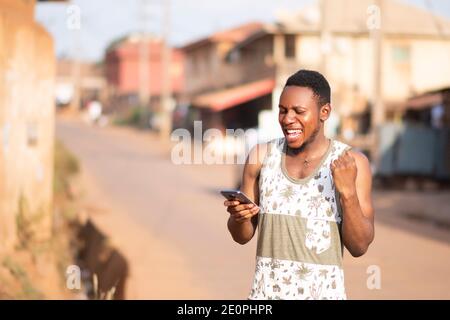 young african man checks his phone and gets excited Stock Photo