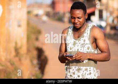 young african man texting on his phone outside on a sunny day Stock Photo