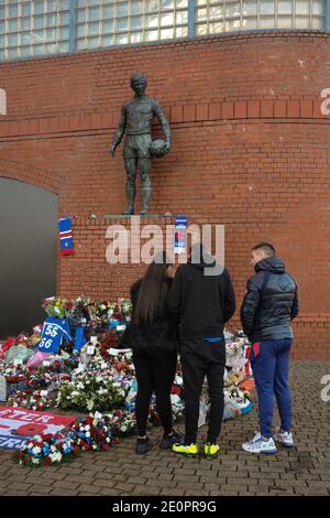 Glasgow, UK, 2 January 2021. Supporters of Rangers Football Club leave flowers and scarves at a memorial (depicting Rangers footballer John Greig) to those 66 fans who lost their life in the Ibrox Stadium disaster which happened 50-years ago today on 2nd January 1971. The anniversary falls on the day that Rangers FC plays their rivals Celtic FC, at home, in a League game. Photo: Jeremy Sutton-Hibbert/Alamy Live News. Stock Photo