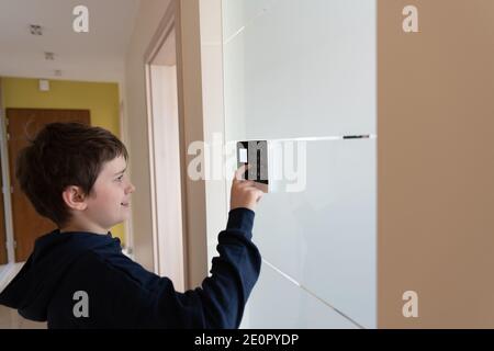 A boy presses buttons on the control panel to disarm the burglar alarm system. Stock Photo