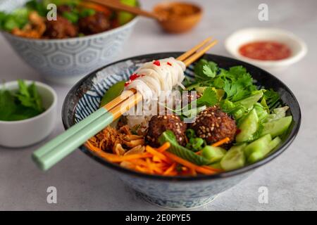 Side view of a Vietnamese bowl of rice noodles with vegetables and spicy dressing on a white background also known as bun cha Stock Photo