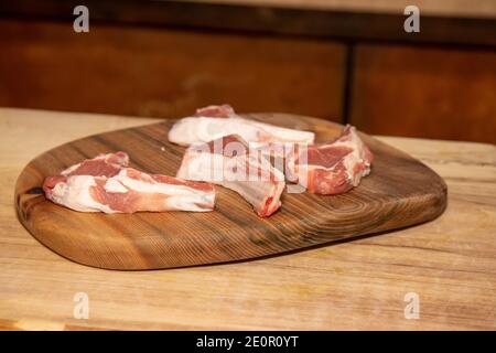Four raw lamb chops on a wooden kitchen work top Stock Photo