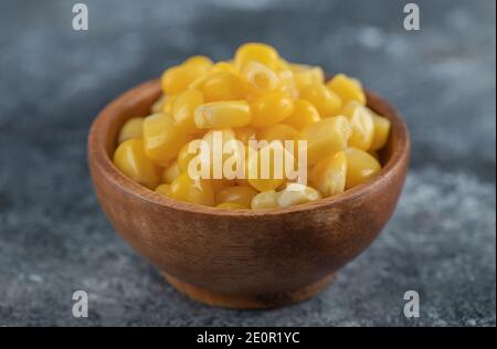 An wooden bowl of popcorn seeds on a marble background Stock Photo
