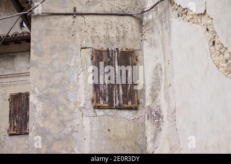 A closed window with wooden shutters in an abandoned building with cracks due to the earthquake (Marche, Italy, Europe) Stock Photo