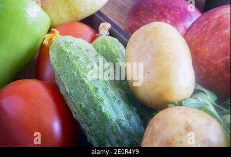 In a small box are cucumbers, tomatoes, apples. Presented in close-up. Stock Photo