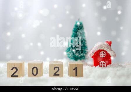 Happy New Year 2021 creative ideas at cubes on snow and background Red house and Christmas tree. Stock Photo