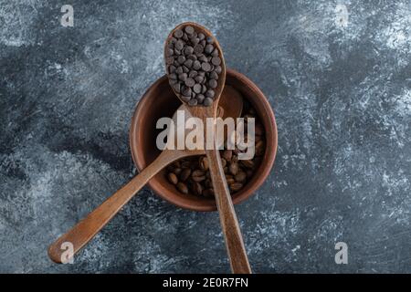 A wooden spoon of chocolate chips with clay bowl of coffee beans Stock Photo