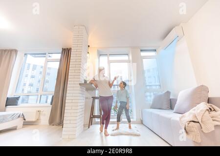 Mother in sportswear with daughter standing near the air conditioning Stock Photo