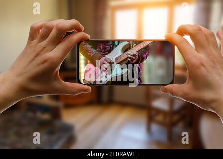 Online music lesson via mobile phone at home. Guitar teacher hands on screen. Stock Photo