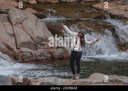 Bretton Woods, New Hampshire, USA -- Sept 25, 2016. A woman poses by a waterfall in the White Mountains of New Hampshire by historic Bretton Woods. Stock Photo