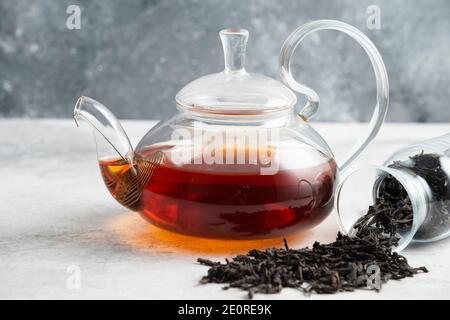 Dry tea leaves with teapot on a marble background Stock Photo
