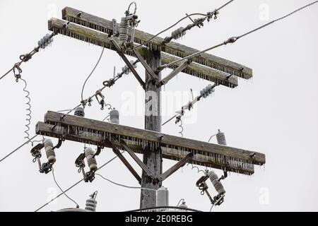 Ice on electrical utility pole and power line from freezing rain. Concept of winter storm and power outage. Stock Photo