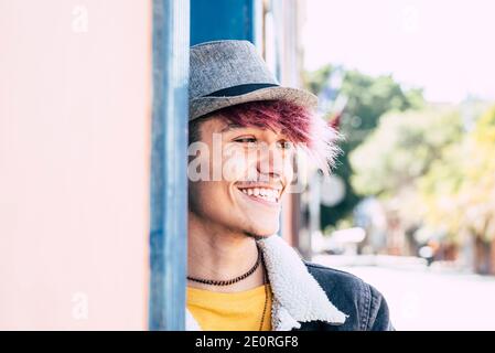Happy cheerful young alternative teenager smile outdoor in diversity concept portrait -violet hair and hat for trendy stylish people enjoying leisure Stock Photo