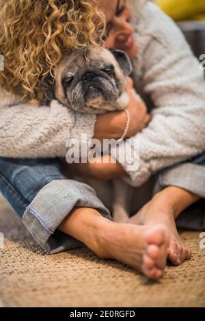 Pet therapy and love animal dog concept with lonely woman at home hugging her own pug on the floor - brown tones image of people hone lifestyle Stock Photo