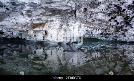 Underground Lake Inside the Ice Cave. Slope of the mountain with the reflection in the water inside a fantastic cave. Kungur In The Urals, Russia Stock Photo