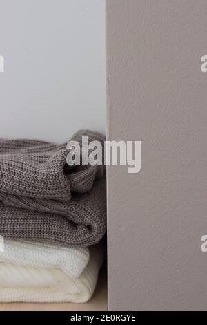 A stack of wool sweaters on the shelf. Grey and white sweater. Warm and cozy. Knitted clothing. Stock Photo