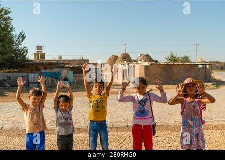 Sanli Urfa, Turkey- September 12 2020: Children posing with hands up for photography at streets of Harran in front of unique harran houses. Stock Photo