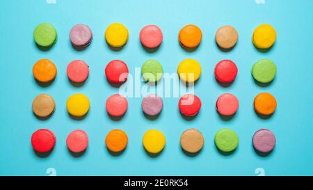 Top view with many homemade macaroons on a blue background. Multicolored macarons isolated on seamless background. Stock Photo