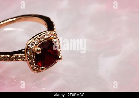 golden ring with ruby stone on pink marble background Stock Photo