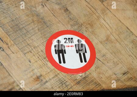 A sign on the floor to guide people to keep 2 metres apart and to follow social distancing rules on a wooden floor Stock Photo