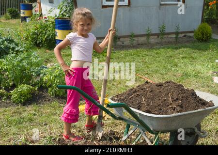 Outdoor activity concept. girl who is transporting rubble in a wheelbarrow. Stock Photo