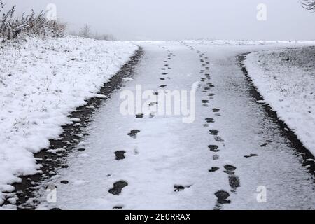 Footprints on the asphalt covered with white snow Stock Photo