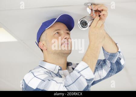 technician man setup cctv camera on wall Stock Photo