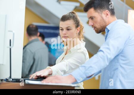 young lady helping middle-aged male adult to use laptop Stock Photo