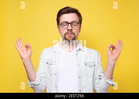 Caucasian funny man meditating on yoga class. Studio shot on yellow wall. Stock Photo