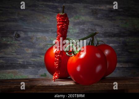 Crushed Red Hot Pepper with Three Tomatoes. On Wooden Background. Stock Photo