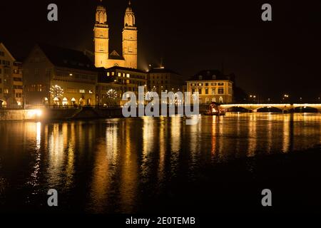 Major church Grossmünster in old town of zurich days before Christmas. View over bridge to a fire place on a raft on the river Limmat. Zurich, 19. Dec Stock Photo