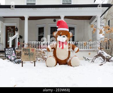 A Christmas yard display with a large teddy bear advertising free hugs during the Covid-19 pandemic of 2020 Stock Photo