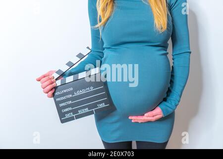 Pregnant woman holding movie clapperboard isolated on white Stock Photo