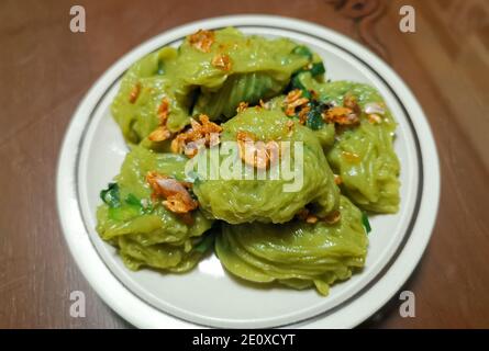 Chinese Chive Dumplings, Stir-fried chives wrapped in thin pandan flavor dough, sprinkled with fried garlic. A kind of snack in Thailand. Stock Photo