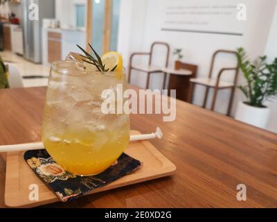 Yuzu orange drink with soda with ice. The drink splits the orange juice and soda into two different colors. The background is a blurry cafe. Stock Photo