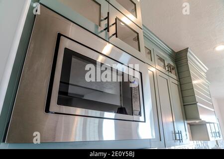 Built in microwave oven and wall cabinets inside the clean kitchen of home Stock Photo