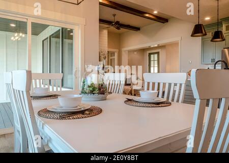 Dinner table for four persons with living area and kitchen view in background Stock Photo