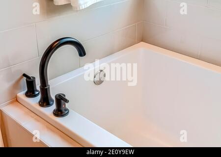 Rectangular built in bathtub inside bathroom of a home with white tiles wall Stock Photo