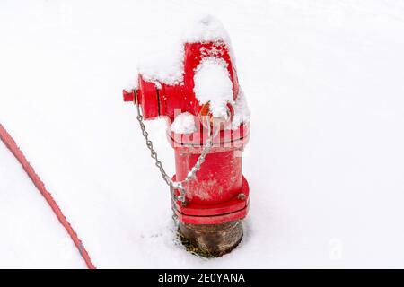 Old fire hydrant with bright red paint on a snowy and frosty winter setting Stock Photo