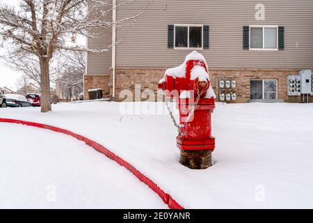 Bright red fire hydrant on the roadside of community covered with snow in winter Stock Photo