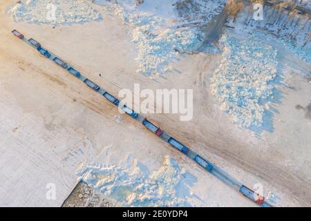 Harbin. 19th Dec, 2020. Aerial photo taken on Dec. 19, 2020 shows ice cube transport trucks lining up along the frozen Songhua River in Harbin, northeast China's Heilongjiang Province. Harbin, dubbed China's 'ice city', attracts tourists by making the best use of ice element during the winter time. Credit: Xie Jianfei/Xinhua/Alamy Live News Stock Photo