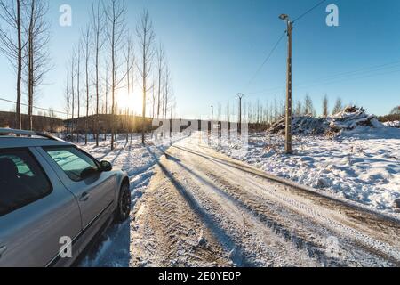 Car on a side of a winter snowy road on a sunny day after the snowplow. Stock Photo