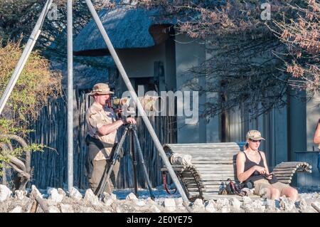 ETOSHA NATIONAL PARK, NAMIBIA - JUNE 13, 2012: Photographers at the waterhole viewpoint at Okaukeujo Rest Camp Stock Photo